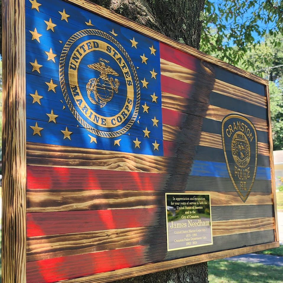 Wooden plaque with U.S. flag design attached to a tree